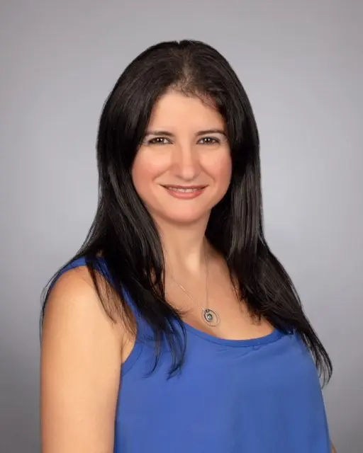 A woman in blue shirt smiling for the camera.