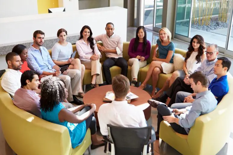 A group of people sitting around each other in a room.