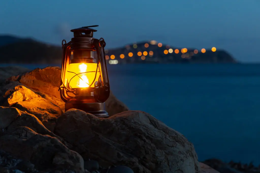 Frontal view of an old oil lantern sitting on a rock of the beach of Cala Regina.